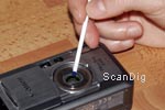 Vorsichtiges Entfernen von winzigen Schmutzpartikeln von einem Kamera-Objektiv